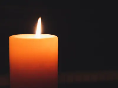 A close up of a burning candle to symbolize memorial.