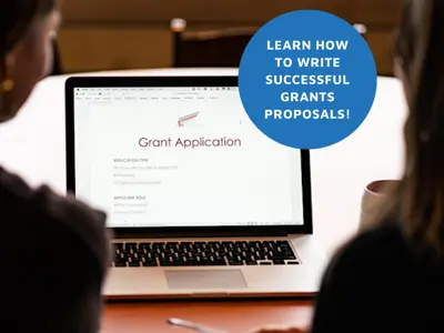 Two people looking at laptop screen displaying a grant application