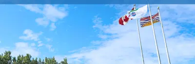 Flags at the Peace River Regional District office flying at half-mast under a blue sky
