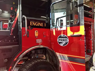 A close up for a red fire truck with Engine 1 and the Peace River Regional District logo decaled on the vehicle.